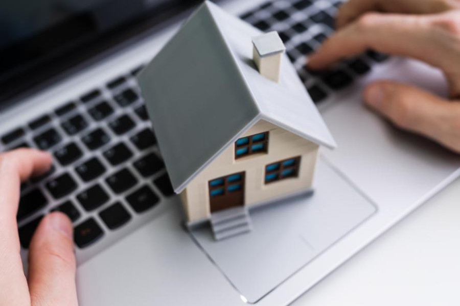 Miniatura de uma casa sobre um portátil, representando a transferência de crédito habitação e poupança nas prestações mensais